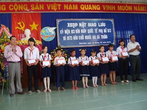 Ông Bùi Minh Tuấn - Phó Bí thư Thành uỷ (bên trái) và ông Nguyễn Thanh Hồng - Trưởng Ban Dân vận Thành uỷ (bên phải) trao học bổng cho học sinh nghèo huyện Bình Đại.