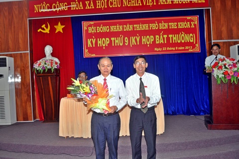 Ông Nguyễn Văn Chanh (bên phải), Chủ tịch HĐND thành phố mới đắc cử tặng hoa cho ông Nguyễn Tấn Đạt thôi giữ chức vụ Chủ tịch HĐND do chuyển công tác khác. (Ảnh: ĐB)